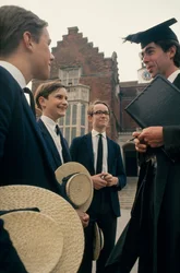 Harrow-elever diskuterar med en lärare framför sin skola.
