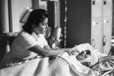 Sjuksköterska hjälper en patient att sträcka sig efter operationen på sjukhusfartyget SS Hope