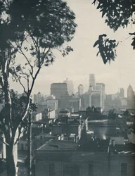 Bostäder av enkelt timmer i skuggan av betongiganter, omkring 1935