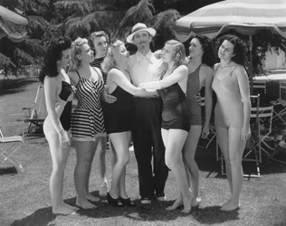 Hollywood, Kalifornien: ca 1935 Sju unga kvinnor i baddräkter tävlar om en ensamstående mans uppmärksamhet. (s/v bild)