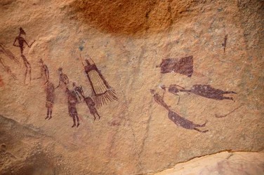 Hällkonst, förhistoria: Hällmålning av en grupp karaktärer och "guerbas" (outerns) har fransar och utan fransar i ett utsmyckat skydd, i Uweinat-massivet, Sudan. Period från 8000 till 3000 år f.Kr. Fotografi