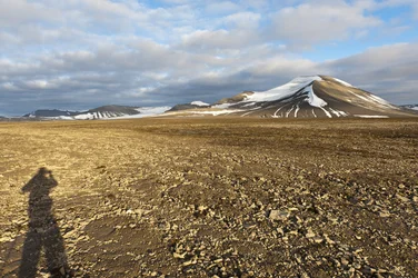 Skugga av en människa, polygonal strukturmark på Plataberget, den snötäckta toppen Nordenskjoeldfjellet i bakgrunden, nära Longyearbyen, Spetsbergen, Svalbard, Norge, Europa