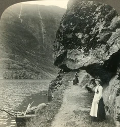Där vägen kryper under de utskjutande klipporna vid vattnet i Nerofjorden, Norge, c1905.