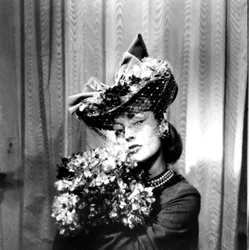 Kvinna som bär en hatt med slöja, håller i en bukett blommor, Paris, 1943