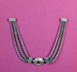 Silverhalsband bestående av en cornelian, i en oval miljö kantad med en kabellist, upphängd mellan två längder av tre kedjor fästa med ett lådliknande spänne, hittat i Great Chesters, mitten 1:a till