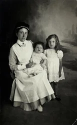 En "sköterska" poserar med barn på 1920-talet.