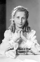 Kristen flicka med händerna sammanfogade i böneställning med bibel, radband och ljus (foto av nattvarden). Fotografering omkring 1932