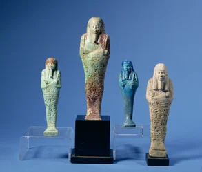 Fyra gröna eller blå glaserade Shabti-figurer, tre med horisontella band med hieroglyfisk inskription, egyptiska, med anor från 700- till 300-talen f.Kr.