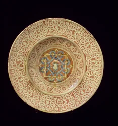 Maiolica-tallrik dekorerad med en utarbetad repetitiv knutdesign som ramar in profilhuvuden på gränsen och en sköld i den centrala plattan, italiensk, tillverkad i Toscana