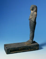Ptah-Sokar-Osiris figur med tredelad peruk och korsade armar på en rektangulär sockel med ett fack som innehåller en sektion av papyrus (se 83304), egyptisk, 21:a-22:a dynastin, c.900 f.Kr. (trä) (för detaljer se 83306)