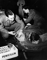 Andra världskriget (1939-1945) - Andra världskriget (WWII eller WW2): Luxemburg februari 1945: På ett evakueringssjukhus i den amerikanska armén administrerar en läkare (sjuksköterska) penicillin till en skadad soldat för att undvika infektion medan en sju