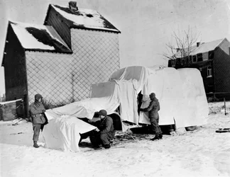 Andra världskriget (1939-1945) - Andra världskriget (WWII eller WW2): Nära Bastogne (Belgien) i slutet av december 1944: Dessa amerikanska soldater använder vita lakan för att dölja en lastbil i fiendens ögon