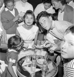 SKÅDESPELAREN OCH FASHIONMODELLEN ELSA MARTINELLI VID DEN XVIII INTERNATIONELLA FILMFESTIVALEN PÅ VENEDIG-LIDO (hon skriver autografer åt unga beundrare. På bordet står en flaska Schweppes) - 1957