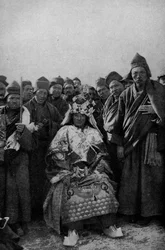 Tibet. Trollkarl i helklädd och ett beundrande band av munkar. 1920