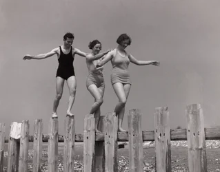 Två kvinnor och en man som går längs en groyne, ca 1930-talet