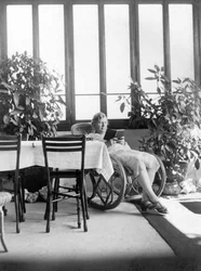 Kvinna sitter i en gungstol och läser en bok. 1915 ca. Tyskland Historiskt foto, kvinna som läser, ca. 1915