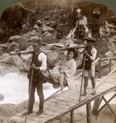 Japansk kvinna i en yamakago bergsstol som korsar den kraftiga Daiya-floden nära Nikko, Japan,