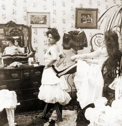 Stereoskopiskt kort som visar en kvinna som knyts in i en korsett, ca 1900 (sepiafoto) (se även 473243)