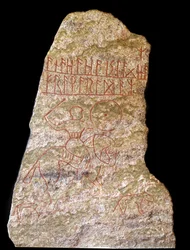 En stele med runinskriptioner som föreställer en vikingaryttare med en hund (sten)