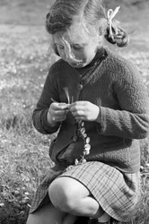 Liten flicka skapar ett halsband av prästkragar