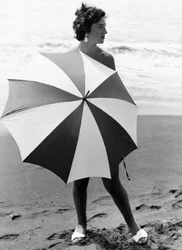 Kvinna med parasoll på stranden, ca 1960 (svartvitt foto)
