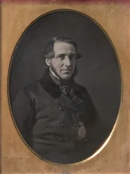 Medelålders man med hakbandsskägg, handstoppad inuti jacka med knäppning, 1840-50-tal