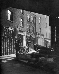 Fruktkorgar staplade mot hus på Borough Market, London, 1926-1927.