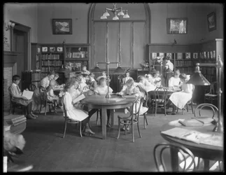 Barn läser i läsrummet i en oidentifierad filial av Queens Borough Public Library, ca 1910.