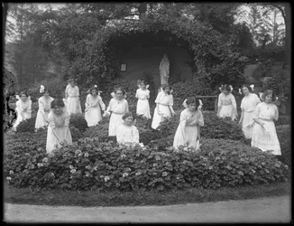 Avgångsklass av flickor från den romersk-katolska föräldralösa asylen i blomsterträdgården, framför Jungfru Marias grotta, 1912 bw foto