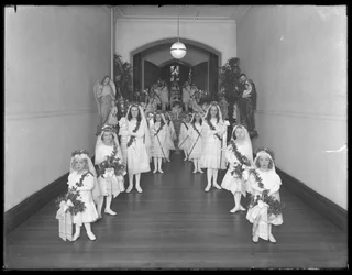 Små flickor på det romersk-katolska barnhemmet Kingsbridge, Bronx, kommer tillbaka från kapellet i vita klänningar med kransar och girlanger, 20 oktober 1914.
