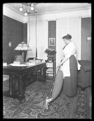 Oidentifierad kvinna som visar användningen av Apex-dammsugaren, ca 1913-14