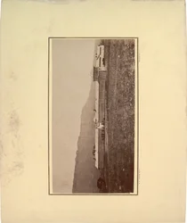 Utsikt över en stockade med flera män samlade vid ingångsporten, 1871 (sepiafoto)