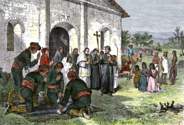 Spansk mission i Kalifornien, med präster, soldater och indianer från Amerika som ber inför kyrkan på 1700-talet