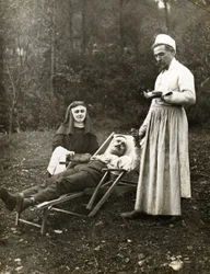 Läkare tar pulsen på en skadad man, assisterad av en nunna, cirka 1900 (s/v foto)