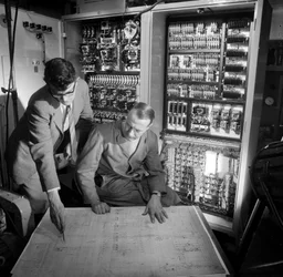 Ingenjörer diskuterar planer framför den elektroniska kontrollpanelen de har byggt